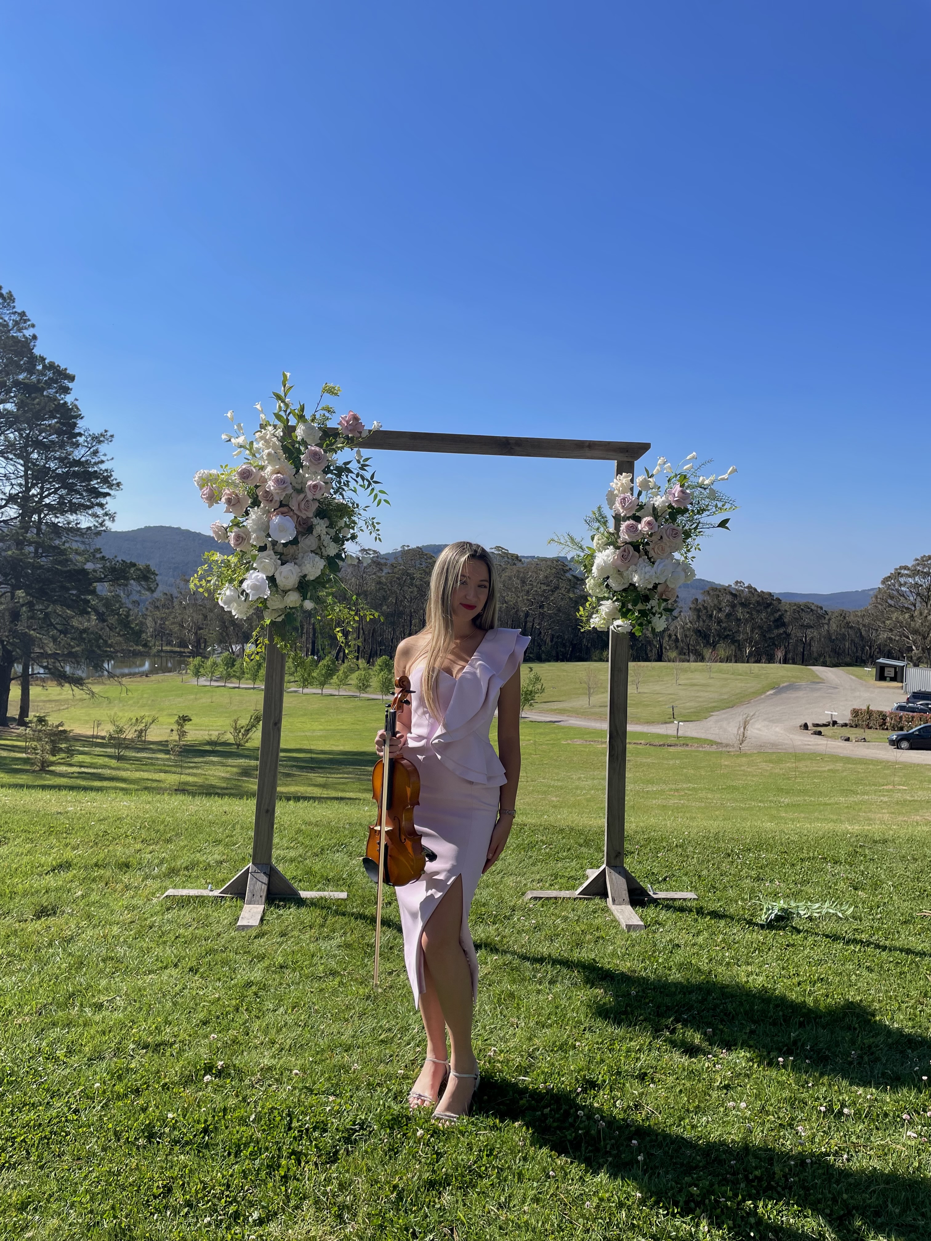 Tali holding violin in front of vineyard